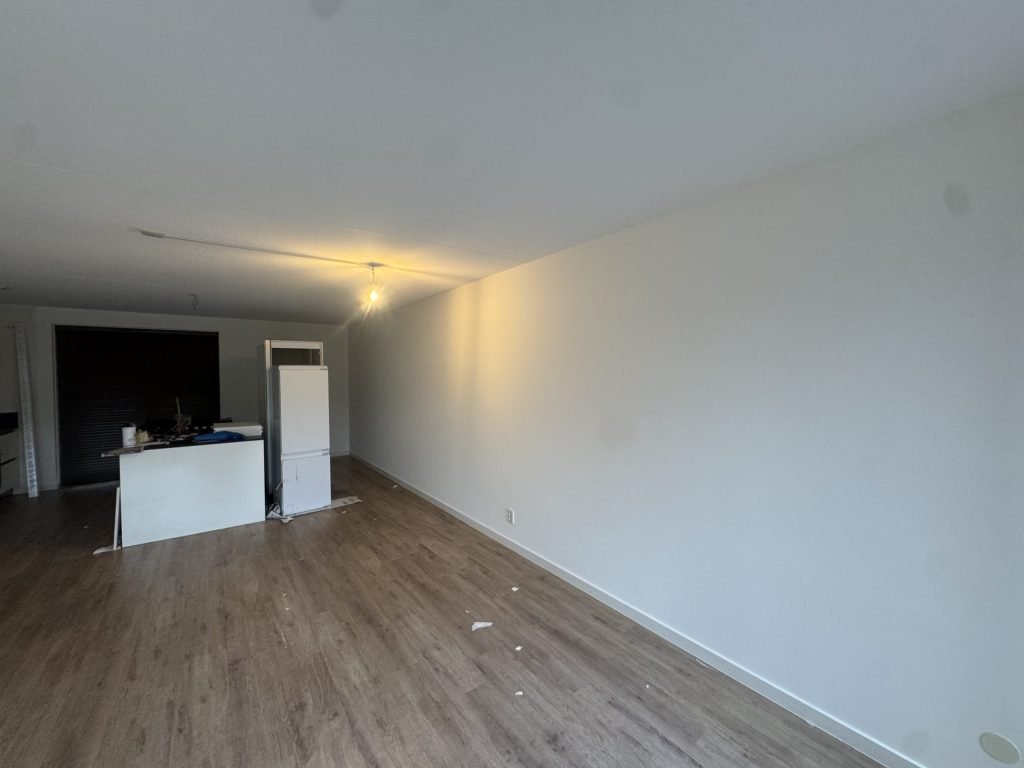 Lange witte wand in een woonkamer met een lamp die schuin langs de muur schijnt